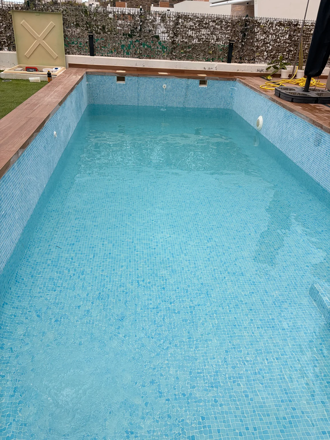 Piscina parcialmente llena con una manguera visible junto al borde